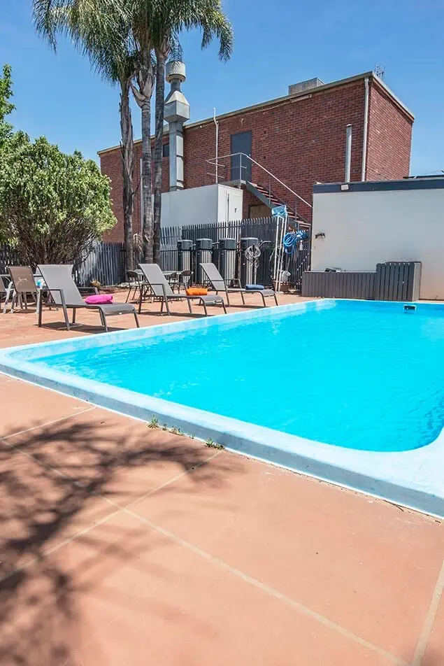 Sun lounges along the edge of the outdoor pool with palm trees behind