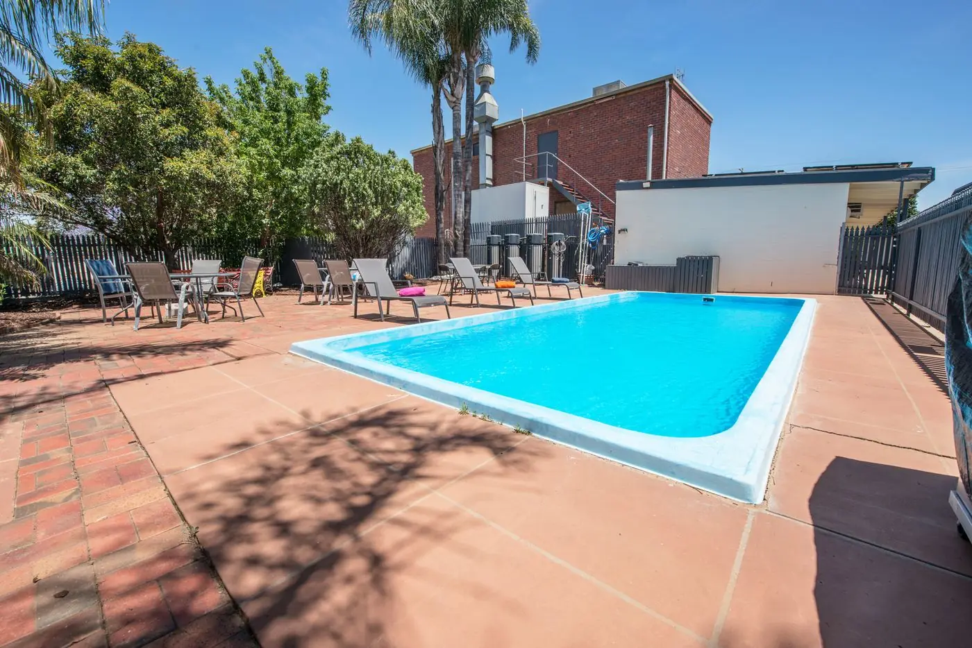 The 12-metre outdoor pool and paved terrace, with sun lounges and shade