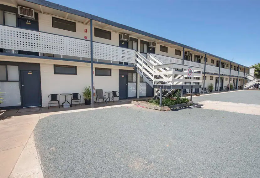Ground-floor motel units with outdoor table settings beneath the first-floor verandah